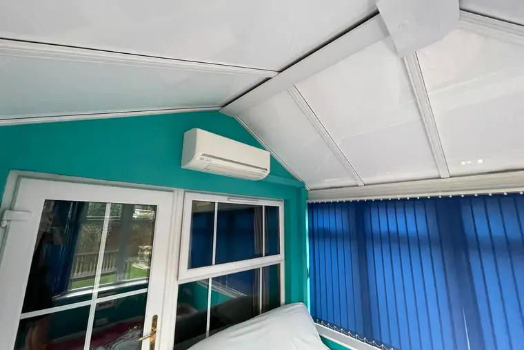 White insulated panel ceiling above a teal gable wall and French doors inside a conservatory